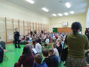 policjantka rozmawia z uczniami w tle telewizor na nim film