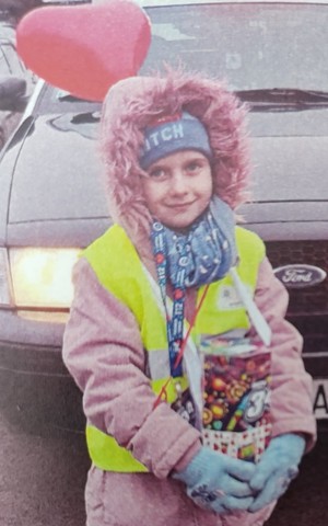 Dziewczynka z puszką WOŚP w tle samochód i czerwony balonik