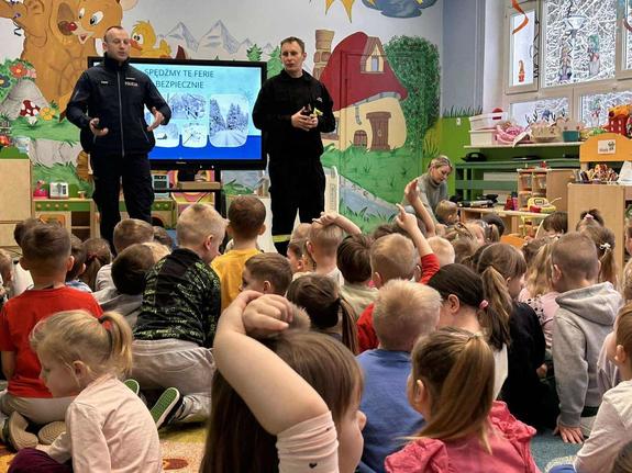 policjanci rozmawiają z przedszkolakami w tle sala