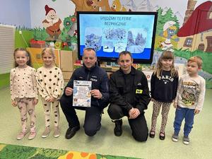 policjanci rozmawiają z przedszkolakami w tle sala