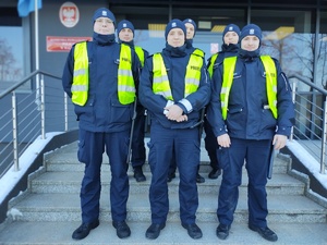 policjanci pozują do zdjęcia w tle wejście do budynku komendy