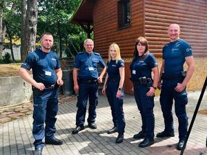 grupa umundurowanych policjantów w tle budynek i zieleń