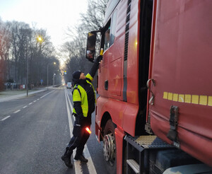 policjant sprawdza stan trzeźwości kierowcy ciężarówki w tle ulica