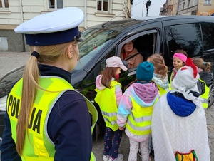 uczniowie i policjanci rozmawiają z kierowcami w tle zabudowania