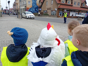 uczniowie i policjanci rozmawiają z kierowcami w tle zabudowania