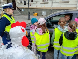 uczniowie i policjanci rozmawiają z kierowcami w tle zabudowania