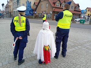 uczniowie i policjanci rozmawiają z kierowcami w tle zabudowania