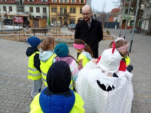 uczniowie i policjanci rozmawiają z kierowcami w tle zabudowania