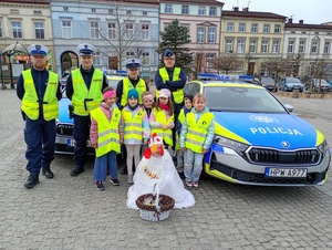 uczniowie i policjanci rozmawiają z kierowcami w tle zabudowania