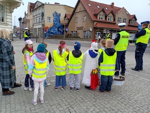uczniowie i policjanci rozmawiają z kierowcami w tle zabudowania