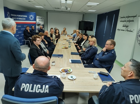 przemowa prokuratora, który stoi przy stole za którym siedzą zaproszeni goście w tle wyposażenie sali