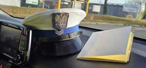 czapka policjanta ruchu drogowego leży na desce rozdzielczej radiowozu w tle zabudowania