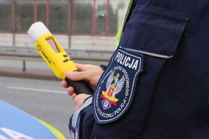 policjant trzyma w dłoni alkotest w tle ulica