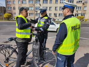 policjanci kontrolują rowerzystów i motocyklistów w tle zabudowania i ulica