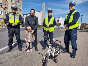 policjanci kontrolują rowerzystów i motocyklistów w tle zabudowania i ulica