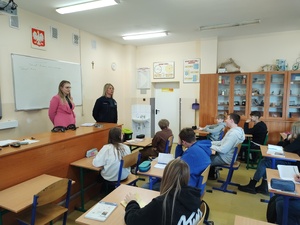 policjantka i przedstawiciel sanepidu rozmawiają z uczniami w tle tablica