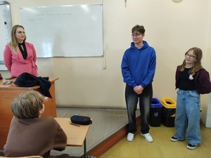 policjantka i przedstawiciel sanepidu rozmawiają z uczniami w tle tablica