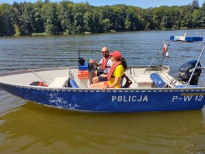 Policjant i ratowniczka WOPR na policyjnej łodzi motorowej w tle jezioro