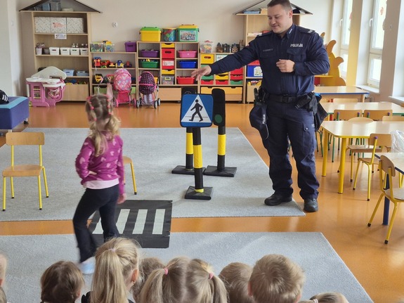 policjant rozmawia z dziećmi w tle sala