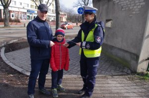 Piesi trzymają odblaski w tel widok osiedla mieskzlnego