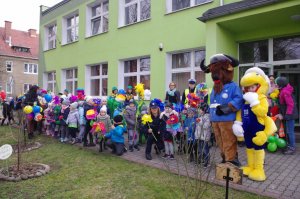Przedszkolaki, policjanci i maskotki pozują do zdjęcia na tle przedszkola