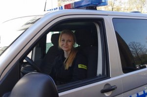 policjanta spogląda przez okno otwarte w radiowozie, na terenie komendy