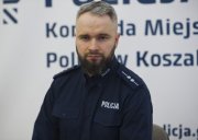 Na fotografii zdjęcie policjanta w mundurze, w tle logo Komenda Miejska Policji w Koszalinie