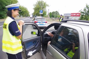 policjantka wręcza kierowcy siedzącemu w aucie serce Kampanii PZU, w tle ulica