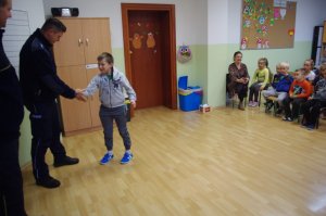 policjant podaje rękę dziecku na powitanie, w tle inne dzieci