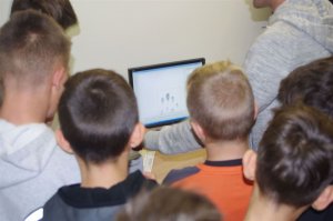 u technika kryminalistyki,  w tle uczniowie wpatrzeni w ekran urządzenia do daktyloskopii