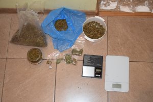narkotyki znajdujące się w woreczkach, plastikowym pojemniku i szklanym leżące na kafelkach podłogi