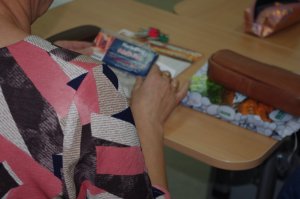 nauczyciel trzyma w rekach materiał poglądowy w postaci narkotestera, w tle ławka