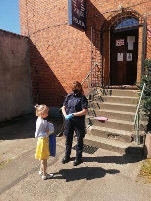 policjantka wręcza nagrody dzieciom,  w tle budynek posterunku policji