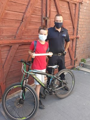 policjant i rowerzysta, w tle budynek policji
