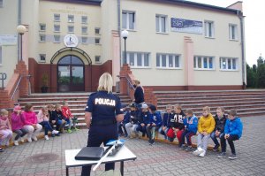 policjantka rozmawia z uczniami w tle szkoła i zabudowania