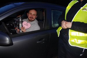 policjantka wręcza znicze, w tle droga