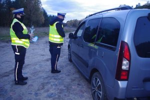 policjantka wręcza znicze, w tle droga