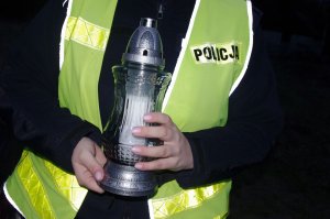 policjantka trzyma w dłoniach znicz, w tle mundur z kamizelką odblaskową