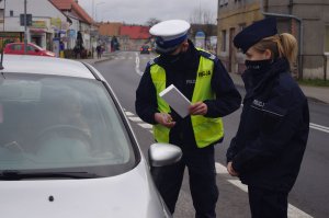 policjanci wręczają prezenty kierowcom, w tle ulica