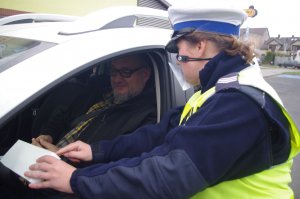 policjantka wyjaśnia kierowcy działanie urządzenia, w tle ulica