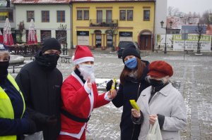 Dwie kobiety pozują do zdjęcia z Mikołajem i policjantami,  w tle zabudowania