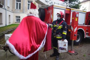 Mikołaj przekazuje prezenty strażakowi