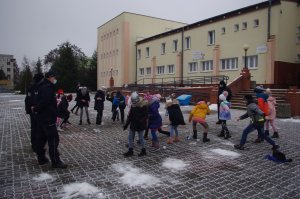 dzieci rzucają się śnieżkami, w tle szkoła