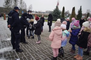 policjantka wręcza dzieciom odblaski, w tle szkoła