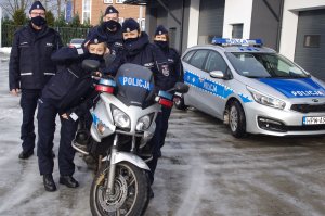 wspólne zdjęcie policjantów przy motocyklu, w tle radiowóz