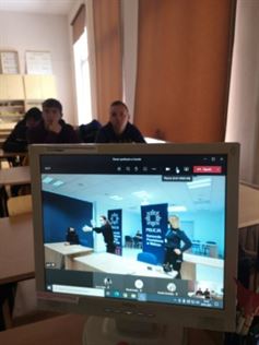 policjantki widoczne na monitorze komputera w tle uczniowie siedzący w ławkach w klasie