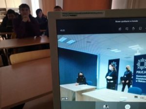 policjantki widoczne na monitorze komputera w tle uczniowie siedzący w ławkach w klasie