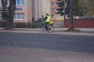rowerzysta w kamizelce jedzie rowerem w tle zabudowania