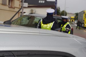 policjanci drogówki podczas kontroli drogowej, w tle pojazdy i ulica